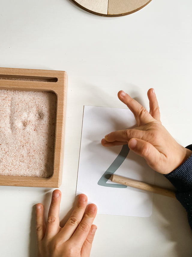 Young child tracing letters on minimalist earth tone Montessori number flashcards to learn how to write numbers