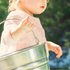 Child independently carries a bucket to complete a gardening task independently