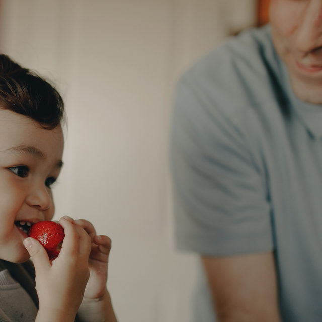 Alt text: A male parent observes his child eating a strawberry and pauses before intervening.